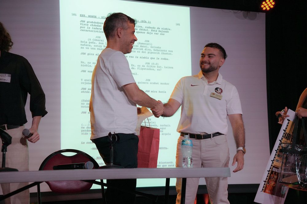 Santiago Reyes shaking hands on stage at an event